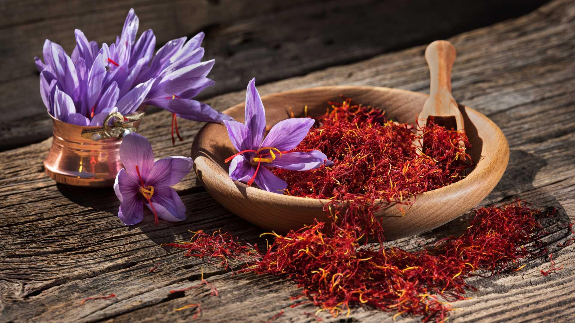 رشتههای زعفران ایرانی و گل بنفش زعفران روی زمینه چوبی